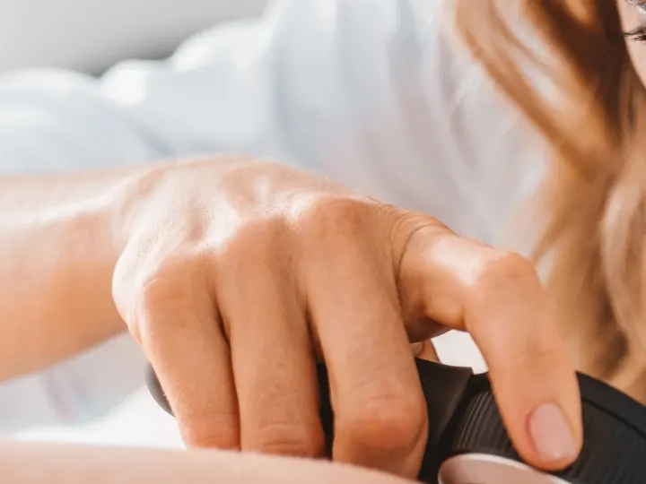 Stock photograph of models: a clinician holds a dermatoscope against a patient's skin and looks closely at it