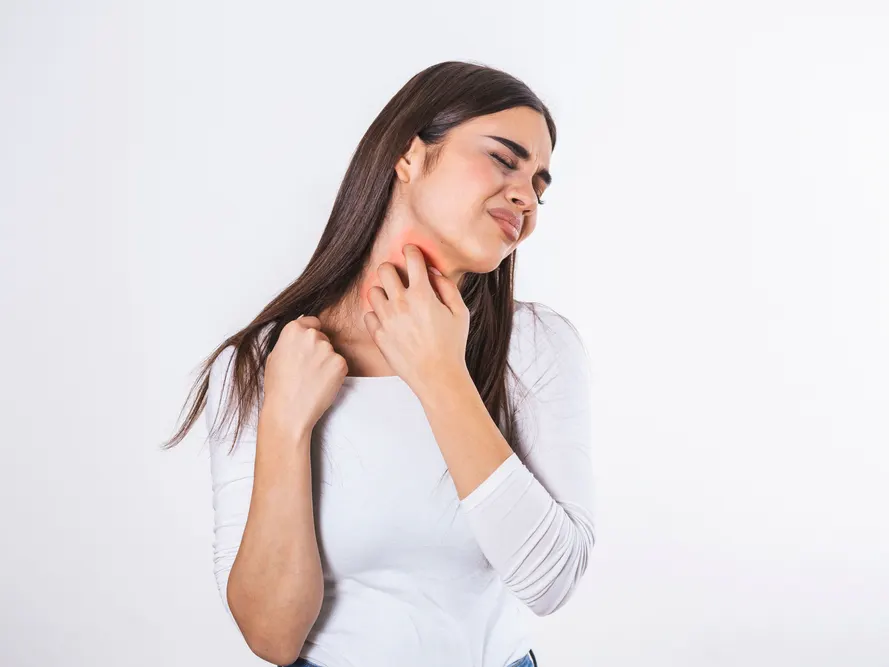 Woman uncomfortably itching her neck due to contact dermatitis rash.