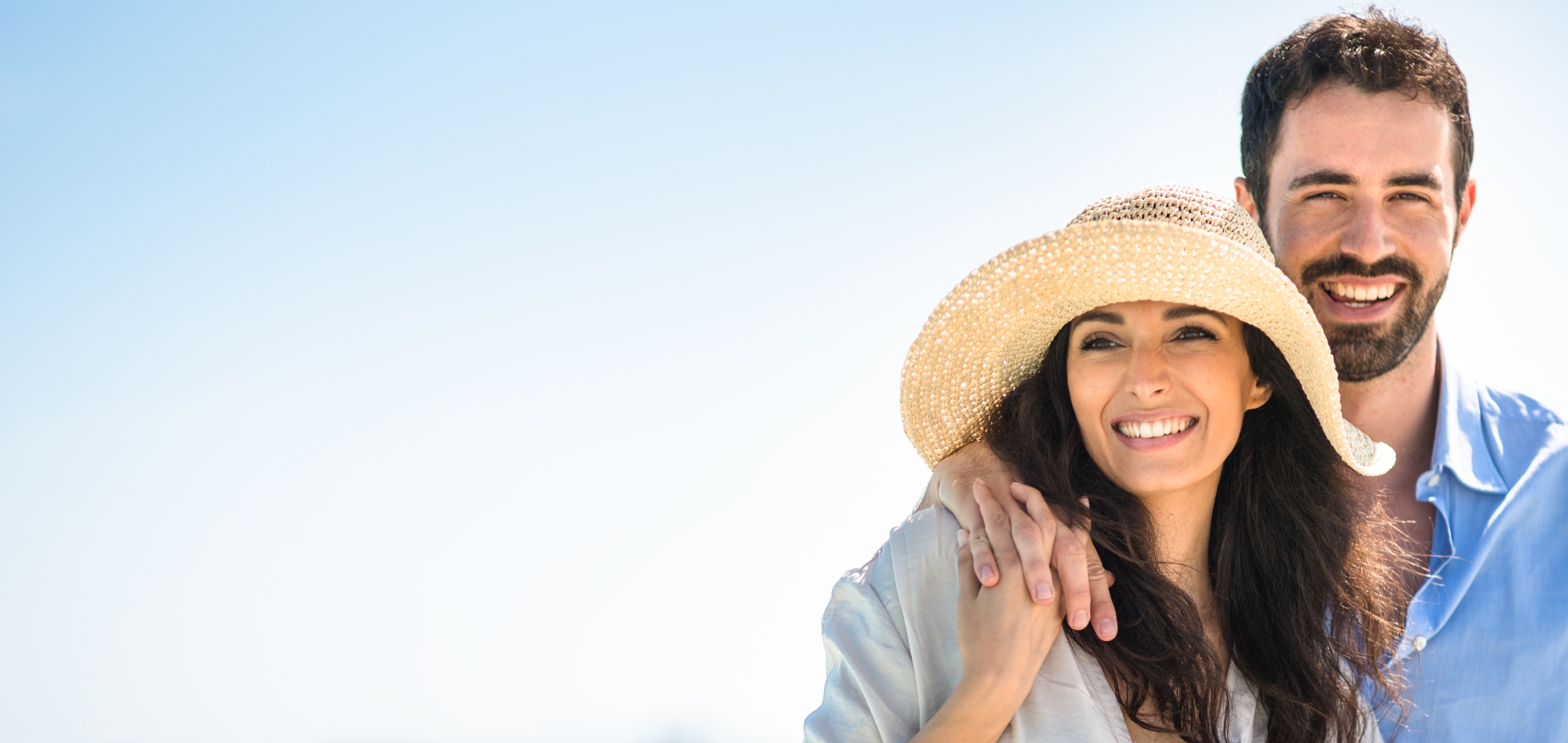 Stock photograph of models: a smiling woman in a sun hat with her partner outdoors