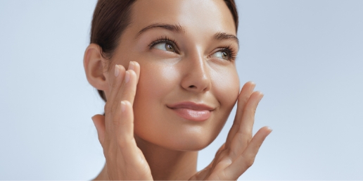 Stock photograph of a model: a woman with glowing skin touches her cheeks with both hands