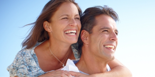 Stock photograph of models: a smiling couple embrace outdoors under a bright sky